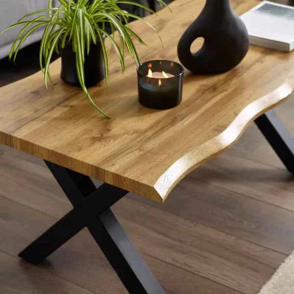 Wooden coffee table with a live edge top and black X-shaped legs.