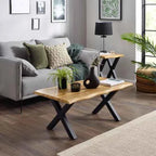 A wooden coffee table with black X-shaped legs sits in a living room.