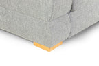 Close-up of a grey fabric sofa corner with a wooden block foot.