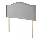 A grey fabric headboard with nailhead trim and wooden legs.