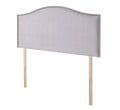 A light gray upholstered headboard with silver nailhead trim and wooden legs.