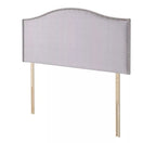 A light gray upholstered headboard with silver nailhead trim and wooden legs.