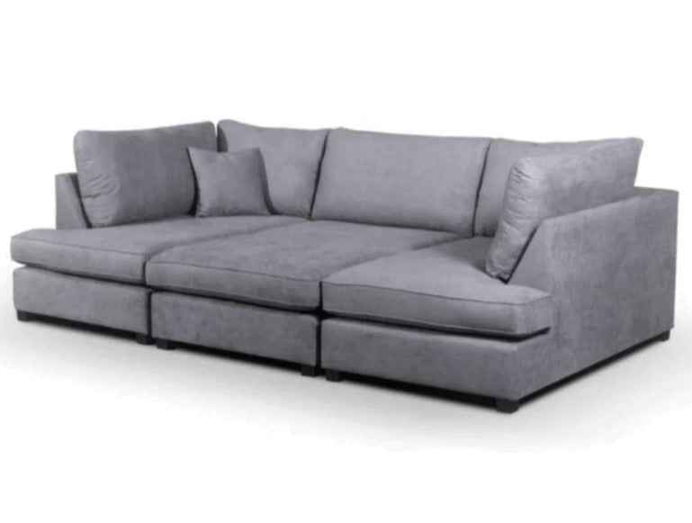 U shaped grey fabric corner sofa with plush cushions.