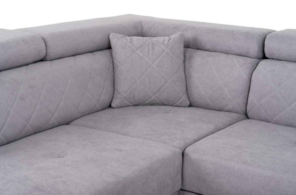 A grey fabric corner sofa with diamond-stitched back cushions and headrests.