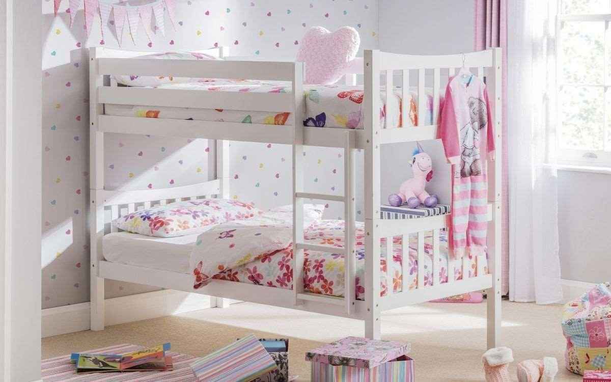 A white wooden bunk bed with floral bedding and a pink unicorn toy.
